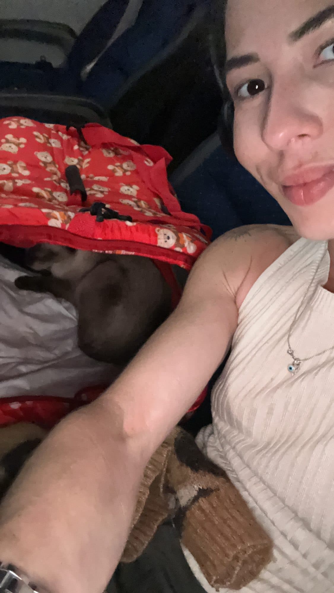 Selfie de Camila junto a una transportadora roja con un gato siamés dentro.