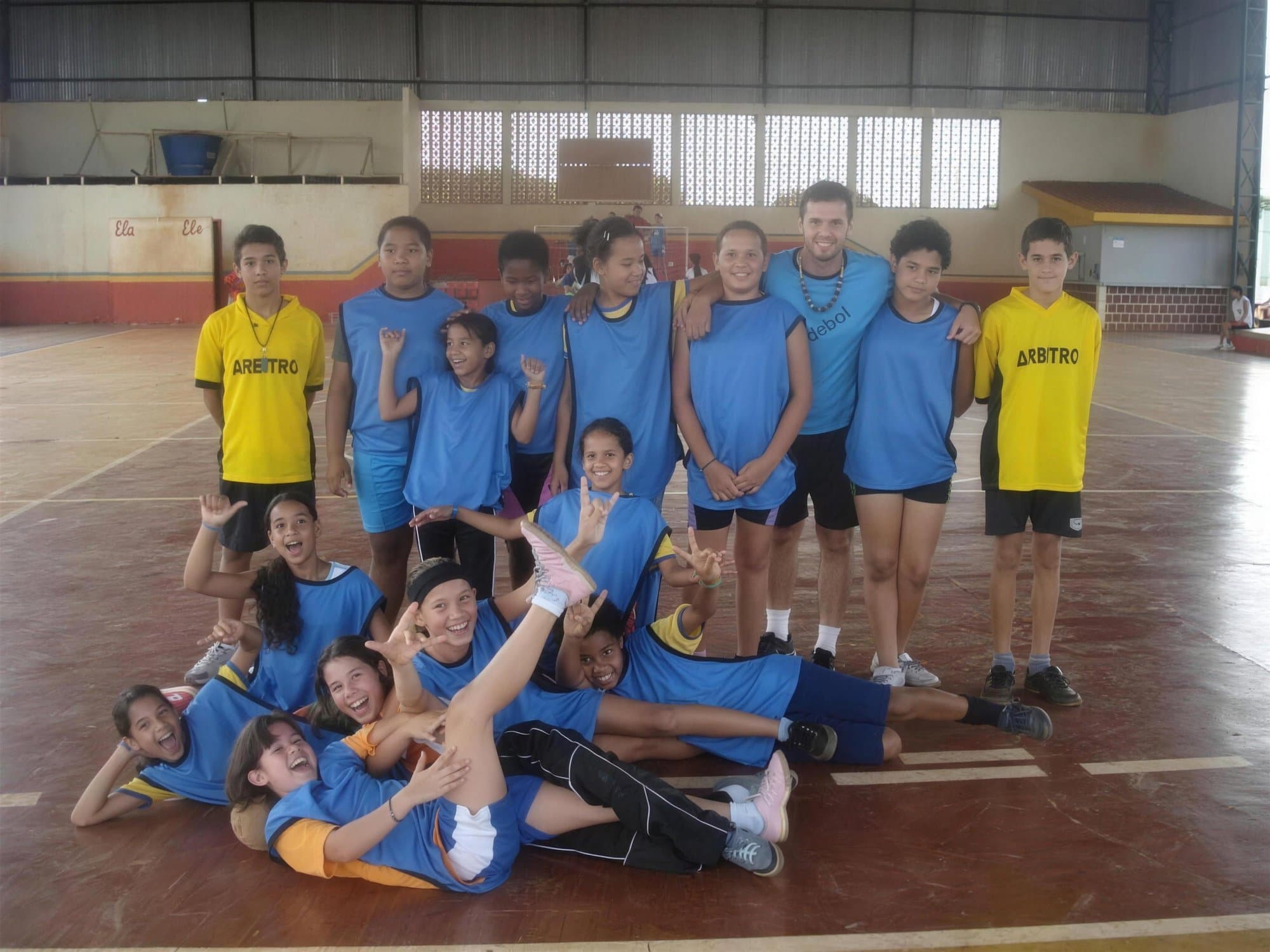 Equipo de handball de niñas, de azul, posando en una cancha cubierta.