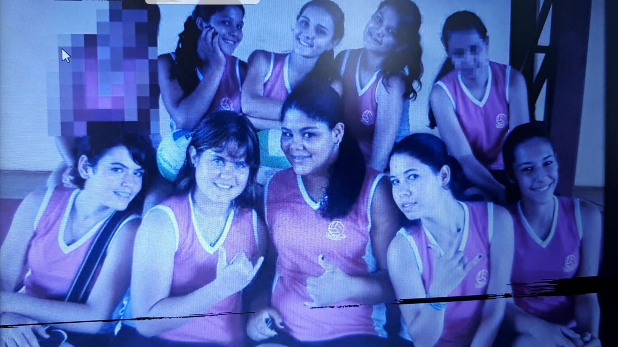 Equipo de vóley de chicas con camiseta rosa, posando juntas con balones.