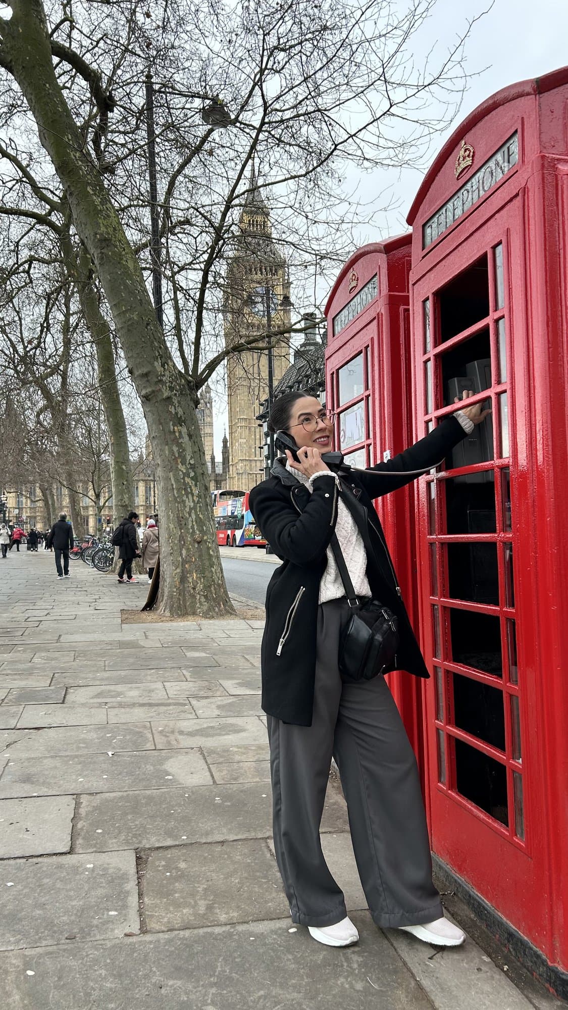 Camila al teléfono en una cabina roja de Londres, con el Big Ben al fondo.
